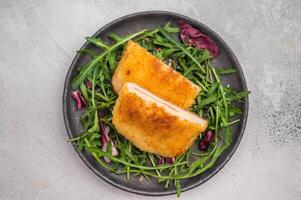Fried Cordon bleu escalopes with salad on plate. white background. top view photo