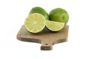 Fresh limes and slices sitting on wooden cutting board photo