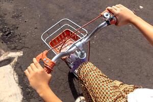 A little girl's hand holding the handlebars of her bicycle. Children's bicycle with basket in front. photo