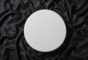 Top view of round white podium stand for cosmetics product presentation on smooth elegant black cloth fabric background photo