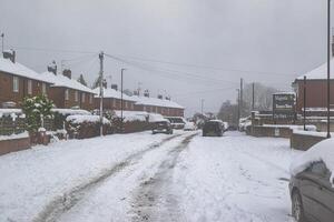 Snow-Covered Residential Street with Parked Cars and Topps Tiles Signage in Harrogate, UK. photo