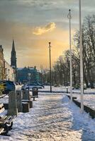 Snow-Covered Town Square with Church Spire and Parked Cars at Sunset in Harrogate, UK photo