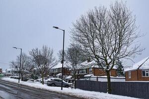 Snow-Covered Suburban Street with Parked Cars and Streetlights in Harrogate, UK. photo