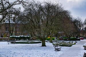 Snowy Park with Benches and Stone Building in Harrogate, UK. photo