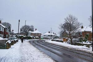 Snow-Covered Residential Street with Houses and Pedestrian in Harrogate, UK. photo