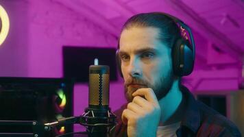 Pensive Caucasian man pondering male blogger influencer addict thinking play game solution deciding choice idea eureka reflective gamer player talk microphone smiling at home cyber sport stream blog video
