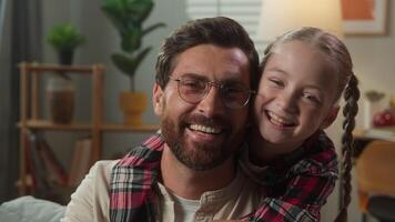 Caucasian family portrait Caucasian man male father good relationship smiling happy looking at camera little girl child kid daughter hugging cuddling embrace dad by neck at home insurance health loan video