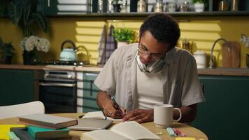African American student ethnic guy teenager freelancer business man working studying at home kitchen writing notes quarantine homework write in notebook looking at camera happy smiling thumb up good video