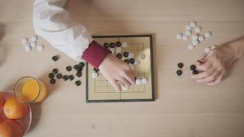 Close up and top-view shots of Go, oriental checkers board game on wooden table are played by two Asian players, leisure time hobby, strategy decision and tactic challenge with compete concentrate. video