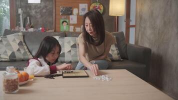 Asian mum and kid fun playing Go, checkers board game on table in home living room together with love and cheerful, happy weekend relaxing hobby of child and parent, concentrate and compete. video