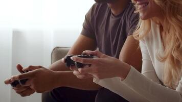 A biracial couple sits closely on a sofa, engaged in a game. They share smiles and laughter, showcasing their love and connection in a warm, intimate atmosphere at home. video