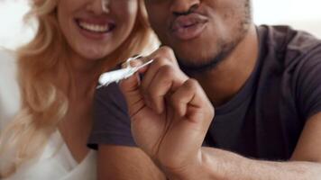 A biracial couple smiles joyfully while spending quality time at home. Their love and connection shine through as they share a playful moment with a pen in hand, emphasizing their bond. video