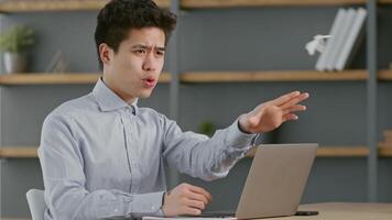 A millennial man reviews important documents while seated at his home office desk. He is focused, utilizing a laptop, and surrounded by minimalistic decor. It reflects a productive work environment. video
