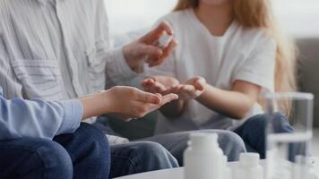 Two family members are applying hand sanitizer in a cozy indoor setting, emphasizing hygiene and health. The casual atmosphere reflects a caring, safe environment. video