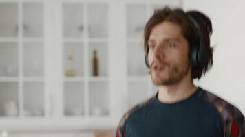 A young man exercises in a modern home environment, wearing headphones and focused on his workout routine. His active lifestyle showcases commitment to fitness and health, copy space video