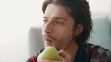 A young man takes a moment to enjoy a fresh fruit snack while working out at home, focusing on maintaining a healthy lifestyle. He looks relaxed and content. video