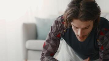 A young man practices his workout routine in a comfortable home setting. He is deeply engaged in fitness activities, showcasing determination and effort while exercising. video