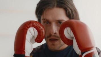 A young man is engaged in an intense boxing workout at home, demonstrating determination and focus as he practices his technique with boxing gloves. video