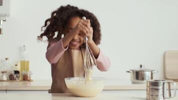 The young girl is energetically whisking batter, while surrounded by ingredients and kitchenware. video