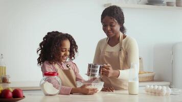 A mother and her daughter engage in a joyful baking activity at home. They mix ingredients in a bowl while sharing smiles and laughter, creating fond memories in the kitchen. video