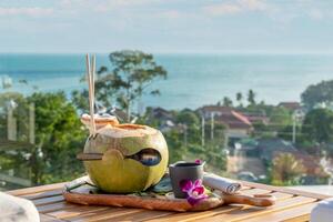 Fresh coconut water with city and sea view in the background at sunset photo
