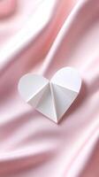 delicate white paper heart resting on soft pink fabric, symbolizing love photo