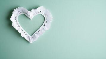 a delicate lace doily in shape of heart on mint background photo