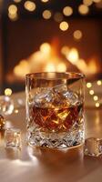 Glass of whiskey with ice cubes, in front of fireplace. Burns Night, Whiskey Day vertical image photo