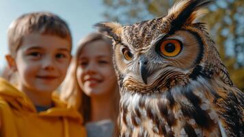 Majestic owl with striking orange eyes, with two smiling children observe it. Festival of Owls Week photo