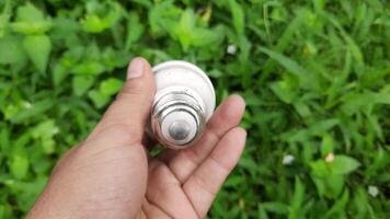 Discovering a damaged light bulb while exploring a lush green area in nature video
