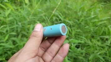 Footage showing a lithium battery being held by a person against a backdrop of green grass video