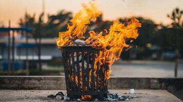 Trash can engulfed in flames, vividly illustrating concepts of fire safety, vandalism, and destruction in an urban environment. Emergency response concept photo