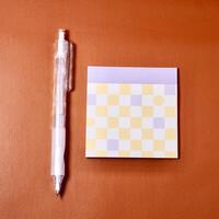 Purple and yellow sticky memo paper and mechanical pencil isolated on square copy spaced orange brown terracotta colored background from top angle view. photo