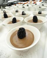 Chocolate mousse with blackberries in white bowls at dessert buffet photo