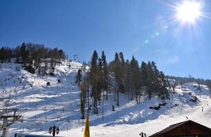 A snowy mountain slope with a ski lift in the background photo