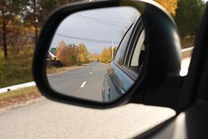 view through the side mirror of the autumn forest photo