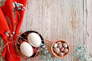 A blank card awaits a message, nestled among delicate white flowers and speckled quail eggs, creating a charming Easter scene. photo