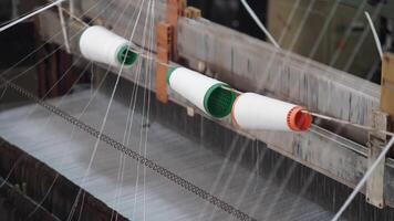 Closeup of a loom and thread spools used in textile production video
