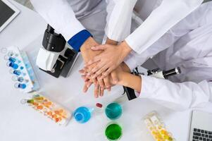 Group of scientists team coordinate handshaking with laboratory equipment and glassware in laboratory. photo