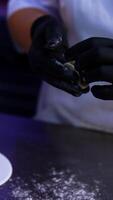 Gloved hands of a cook make the little dumplings. Two people making ravioli with meat at modern food factory. Vertical video