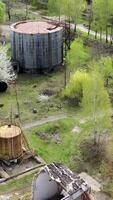 Old industrial territory. Abandoned buildings of ancient factory. Ruined edifices in spring. Old brick pipe of industry. Aerial view. Vertical video