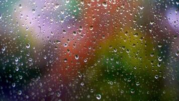 Glass with raindrops. Water drops on window on blurred colorful background. Rain falling outside. Droplets background. Close-up. video