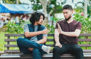 Disgusted guy sitting refusing a cigarette. Young man sitting refusing a cigarette in the park photo