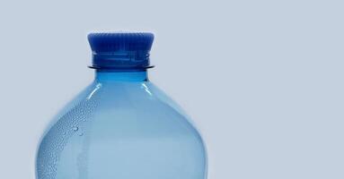 A blue plastic PET water bottle close up isolated on white background with bubble condensation on the surface. Recycling, environment friendly and ecology concept photo