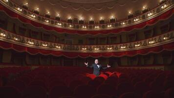 Actor among red seats in empty concert hall. Man in suit standing in beautiful large empty auditorium and talking something. Lockdown in the world. video