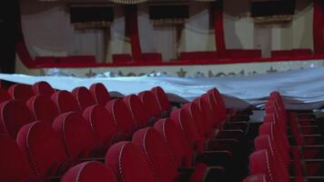 Empty theater hall with red fabric seats. Opera hall with comfortable armchairs without people. Chairs are covering by white material during lockdown time. video
