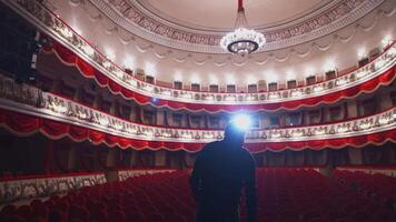 Man on stage in empty theater. Back view of an actor standing on stage and performing in a large theater without people. video