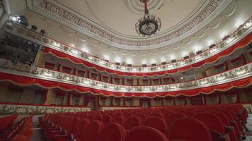 Large theatre hall with nobody. Rows of comfortable armchairs without people in the opera house. Empty red velvet seats inside a theater at pandemic. video