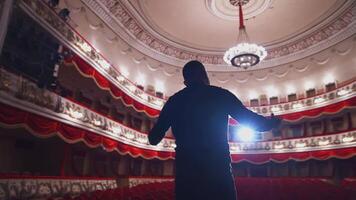 Actor in front of empty theatre hall. Man is standing on stage and talking with gestures before the performance. video