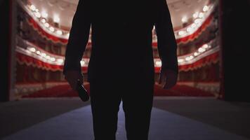 Unrecognizable man in suit on stage. Silhouette of a singer man holding a microphone on the background of empty theater hall. video